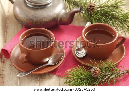 Pine needle tea in cups and kettle, pine twigs Royalty-Free Stock Photo #392541253