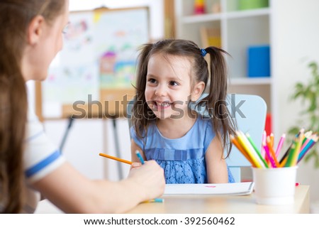 Young woman or mother teaches kid to pencil