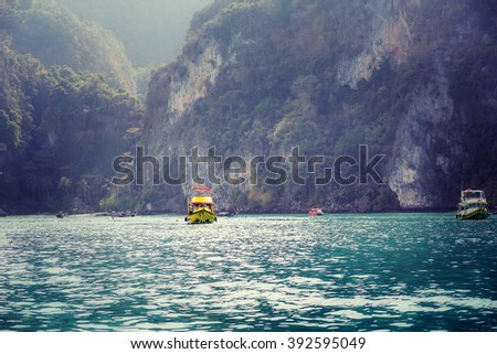 Yellow tourist ship in beautiful seascape of Phi-Phi islands, Krabi, Thailand. Image with selective focus and toning