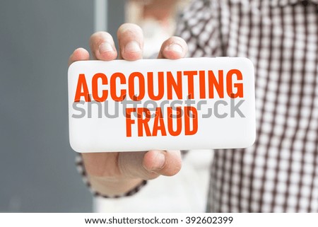 Man hand showing ACCOUNTING FRAUD word phone with  blur business man wearing plaid shirt.