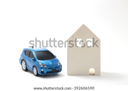 Miniature car and house on white background.
