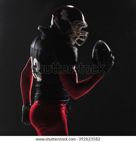 American football player posing with ball on black background - Super Bowl concept