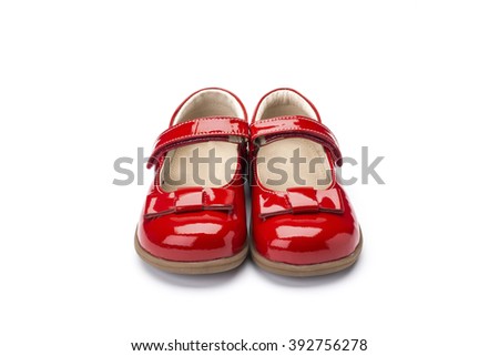 Pair of childs shiny red patent leather shoe with bow design and strap shot at a 3/4 angle on a white background Royalty-Free Stock Photo #392756278
