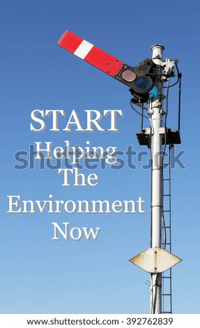 Historic red home British railway signal in the start position with an Inspirational motivational quote of Start Helping The Environment Now against a clear blue sky background.