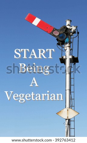 Historic red home British railway signal in the start position with an Inspirational motivational quote of Start Being A Vegetarian against a clear blue sky background.
