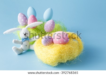 Homemade Hand Painted Easter Eggs of Various Colors in a Nest on blue Background