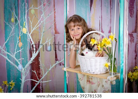 The girl and easter rabbit in a basket on a swing