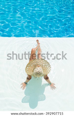beautiful woman in a white hat sitting at the swimming  pool
