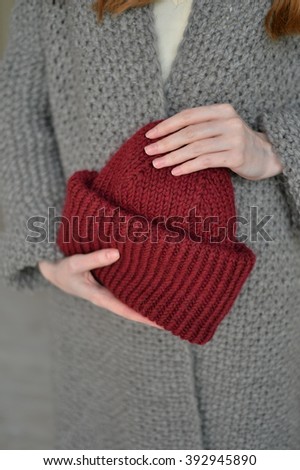 Red knitted cap in her hand