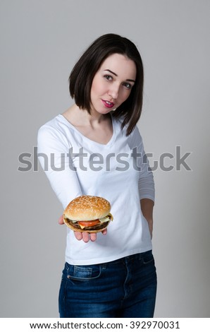 young beautiful girl with a Burger in hand on gray background

