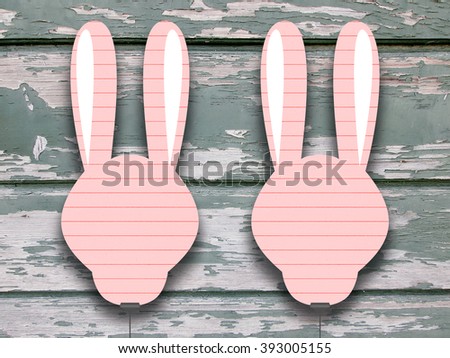 Close-up of two hanged pink blank rabbit silhouette frames with clips against green wooden boards background