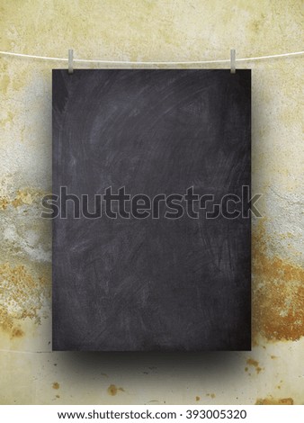 Close-up of one hanged blank blackboard sheet frame with pegs against brown weathered wall background