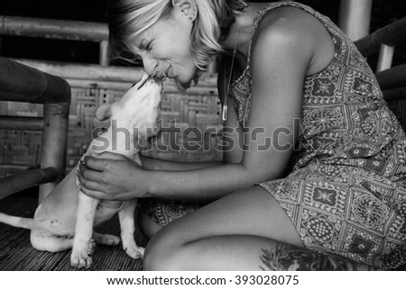 beautiful attractive girl with a tattoo on his leg a little puppy kisses on the nose
