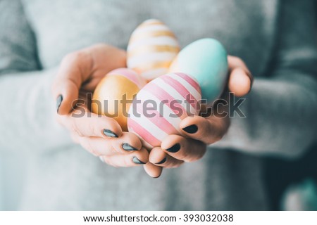 Hands holding modern painted easter eggs. Selective focus. Toned picture