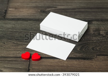Blank card on old wooden table with small red heart.