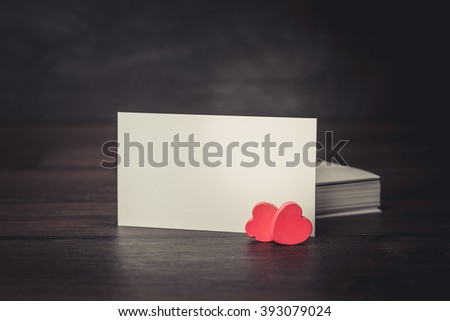 Blank card on old wooden table with small red heart.
