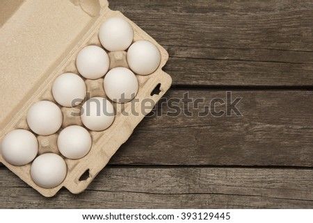 Carton of organic white eggs on wooden board. Top view. Copy space.