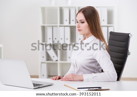 Young businesswoman sitting at table. Office at background. Concept of call work.