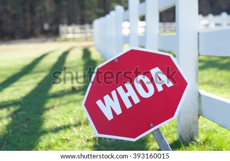 RED OCTAGON "WHOA" (STOP) SING IN FRONT OF HORSE FARM WITH WHITE FENCE
