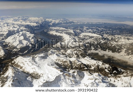 Aerial photo of the landscape with clouds, snowy mountains and view stretching all the way to the horizon