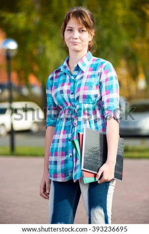 Portrait of young alluring woman holding education books. Student girl.
