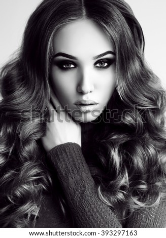 fashion black and white photo of beautiful young woman with dark curly hair, posing in studio