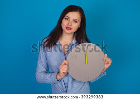 Woman with clock is standing against of blue background