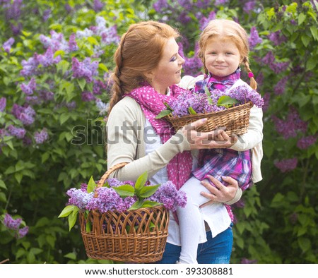 happy mother and daughter in the garden of blooming lilacs