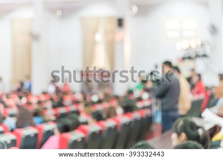 Blurred abstract of cameraman recording/videotaping an event in Hanoi, Vietnam. Campus lecture hall with full of audience in line of red armchairs rows. Blur people background.