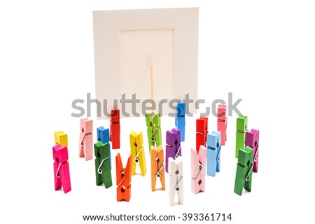 Green clothespin standing in front of a white frame and displays it on a toothpick. Other pegs grouped together