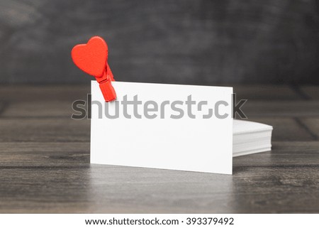 Blank business (visit) card on old wooden table and small red heart. Toned photo.