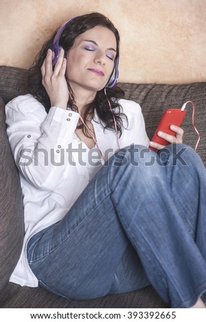 Relaxed middle aged woman listening to music. Toned image with shallow depth of field
