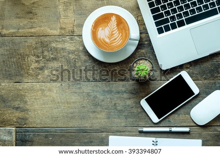 Place of work. Close-up top view of comfortable working place in office with wooden table and laptop coffee of cup smart phone notepad and mouse  laying on it