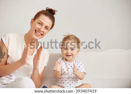 Young mother with her one years old little son dressed in pajamas are relaxing and playing in the bed at the weekend together, lazy morning, warm and cozy scene. Selective focus