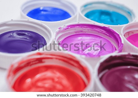 Colorful acrylic paints in covers isolated on table