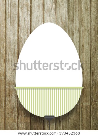 Close-up of one hanged decorated blank Easter egg frame with green lines decoration against brown wooden boards background