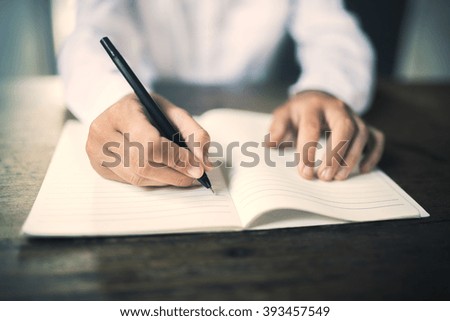 Girl writes in notebook on a wooden table
