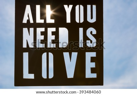 Inspirational quote, all you need is love, against blue sky and sun