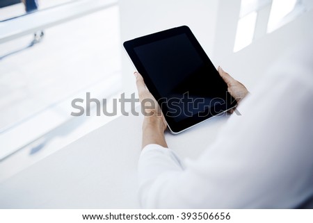 Closeup image of woman`s hands is holding digital tablet with mock up copy space screen for advertising text message or informational content. Female is reading electronic book on portable touch pad