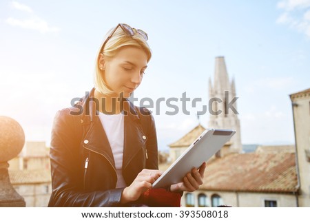 Young gorgeous woman is searching information in website via portable touch pad during her recreation time in vacations. Gorgeous hipster girl is watching photos on digital tablet what she took now