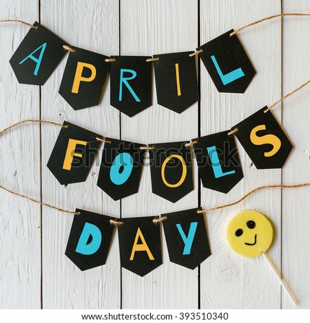 April fools day black banner colorful lettering on white barn wood rustic planks background. Holiday greeting postcard.