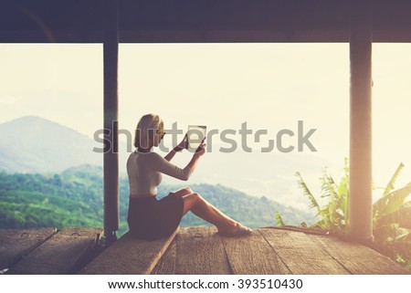 Woman tourist is taking photo with digital tablet camera of an amazing Amazon landscape from viewpoint. Young female wanderer is making pictures on touch pad during unforgettable trip in Latin America
