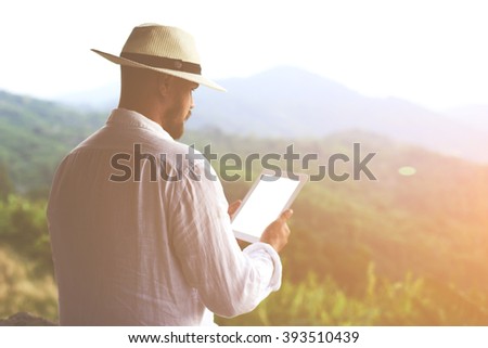 Back view of a male wanderer is holding touch pad with copy space on the screen for your advertising text message or information content. Young man is searching new way in navigator via digital tablet