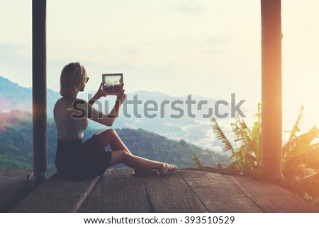 Woman is shooting video on touch pad of beautiful view during her long awaited summer vacation in Thailand. Female wanderer is making photo with digital tablet camera of an amazing jungle landscape