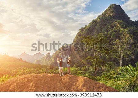 Back view of woman is shooting video with mobile phone camera, while is standing against fantastic Amazon landscape background with copy space for your advertising text message or promotional content