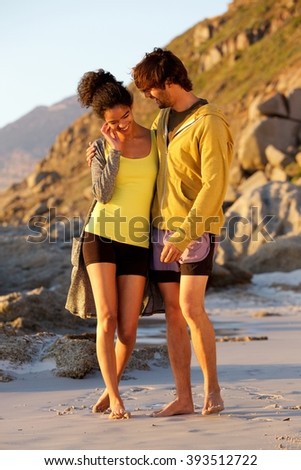Full length portrait of young man and woman embracing at the beach 