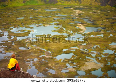 girl sitting on the edge of the Rano Kau volcano, Easter island, Chile, South America