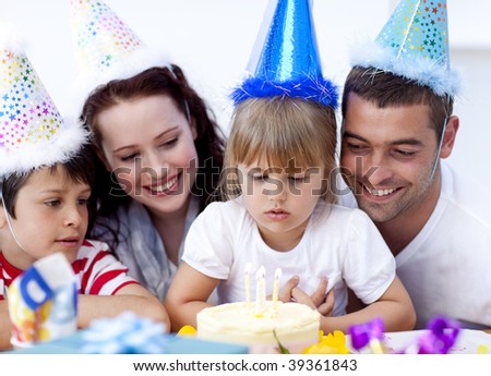 Little girl admiring a cake on her birthday's day with her family