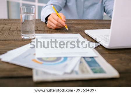 Creative photo of objects and hand on vintage brown wooden table. There are documents and laptop on it