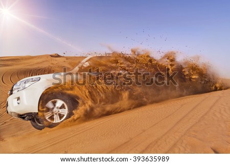 Offroad vehicle bashing through sand dunes in the desert Royalty-Free Stock Photo #393635989